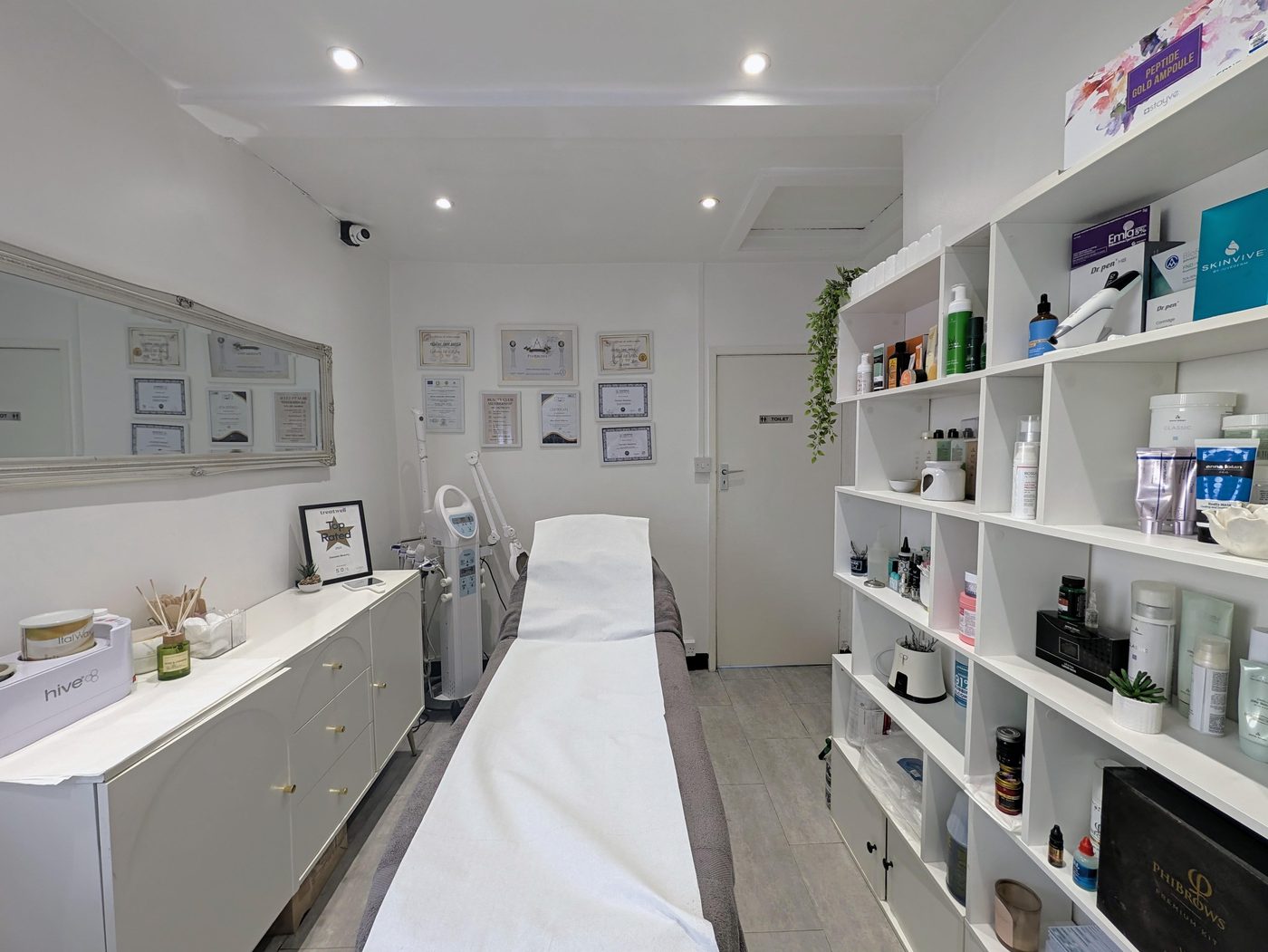 Inside the Beauty by Daniela treatment room in London: treatment bed, product shelves and framed professional certificates